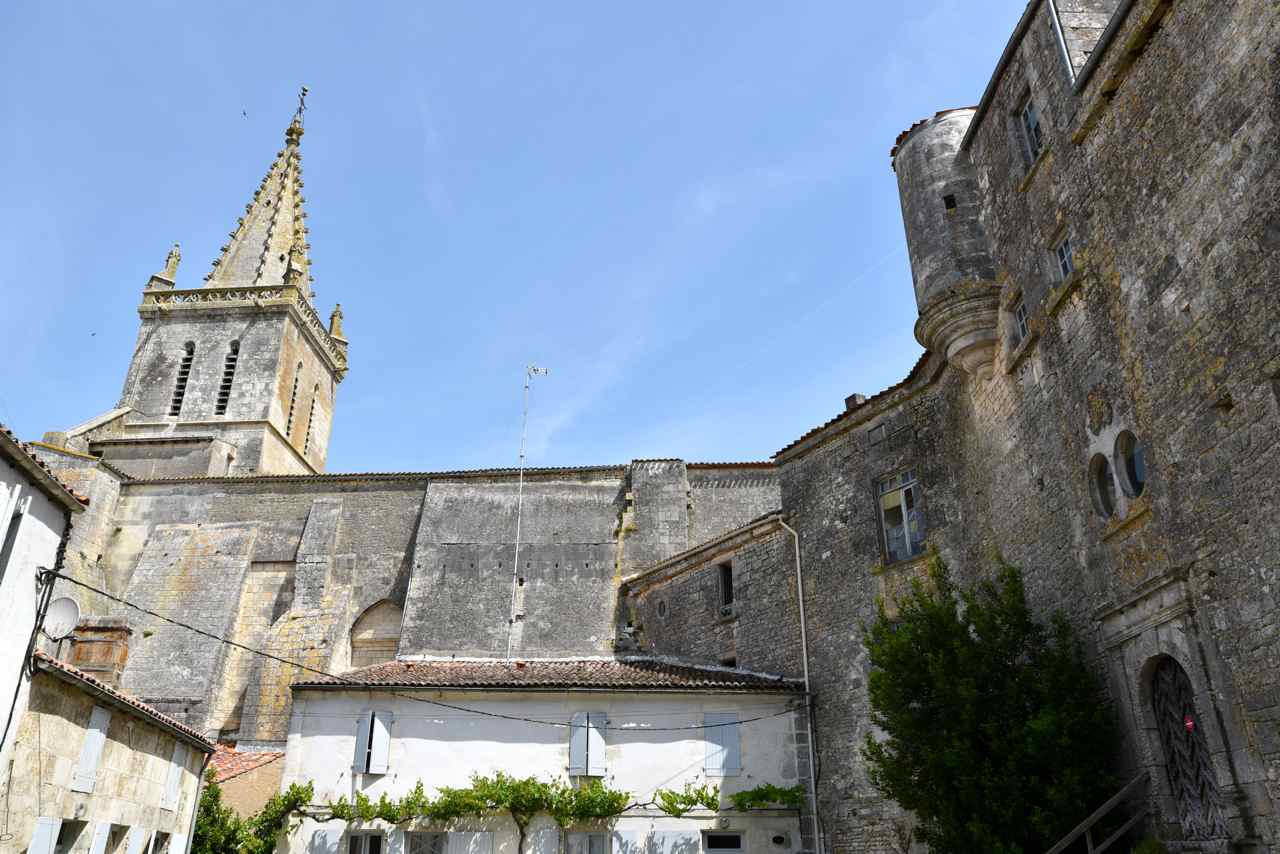 Le clocher massif de l'église et à droite le prieuré ...