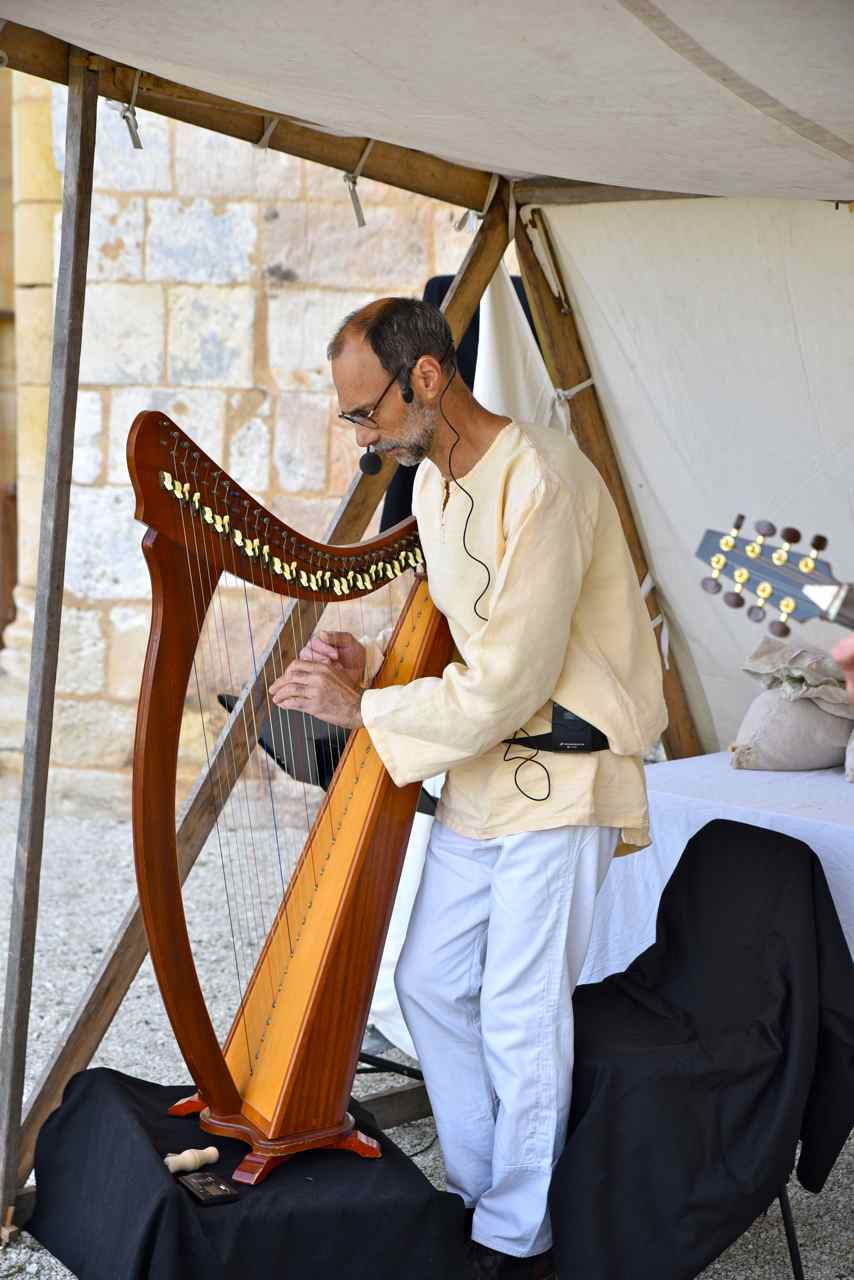 Le musicien joue d'une harpe médiévale dite harpe romane