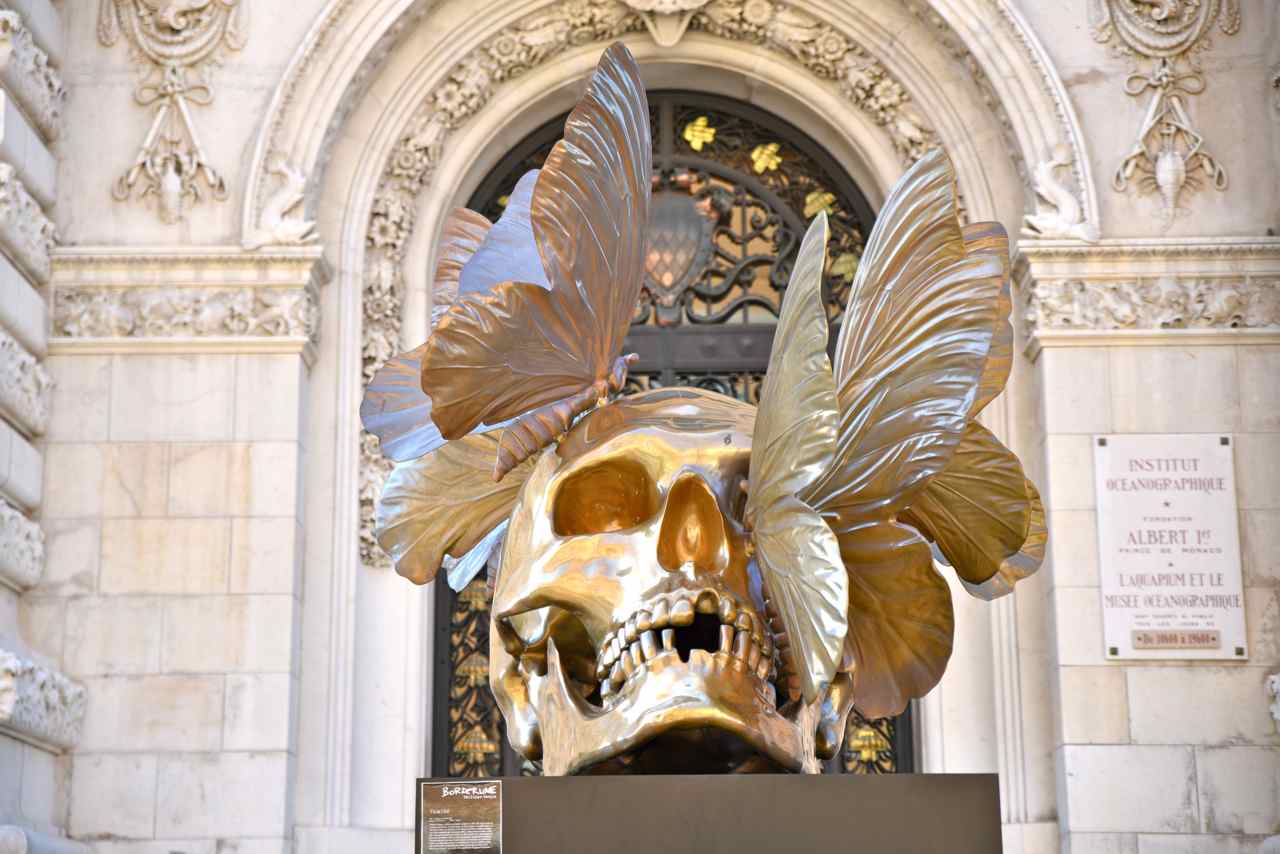 ...un crâne doré (Haut : 3,7 m Poids 1 tonne) surmonté de papillons ...