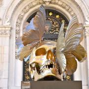 ...un crâne doré (Haut : 3,7 m Poids 1 tonne) surmonté de papillons ...